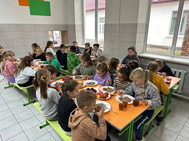 Учні їдять за помаранчевими столами в шкільній їдальні