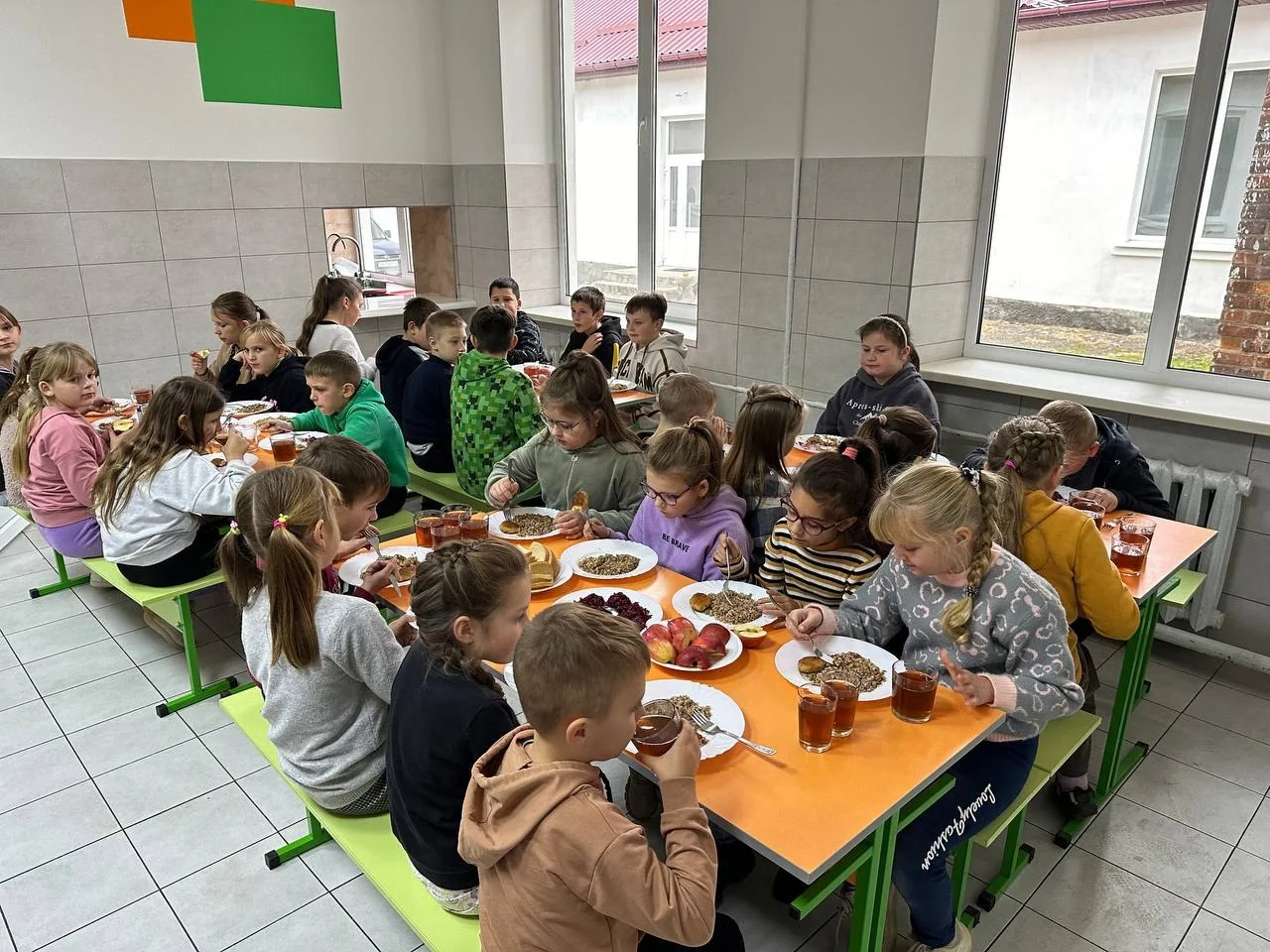 Учні їдять за помаранчевими столами в шкільній їдальні