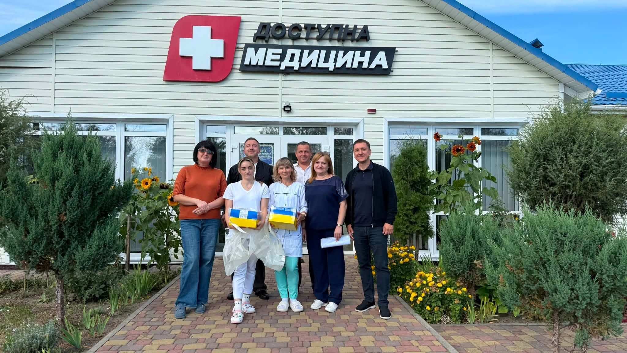 Група людей біля амбулаторії Доступна медицина тримає жовто-блакитні коробки