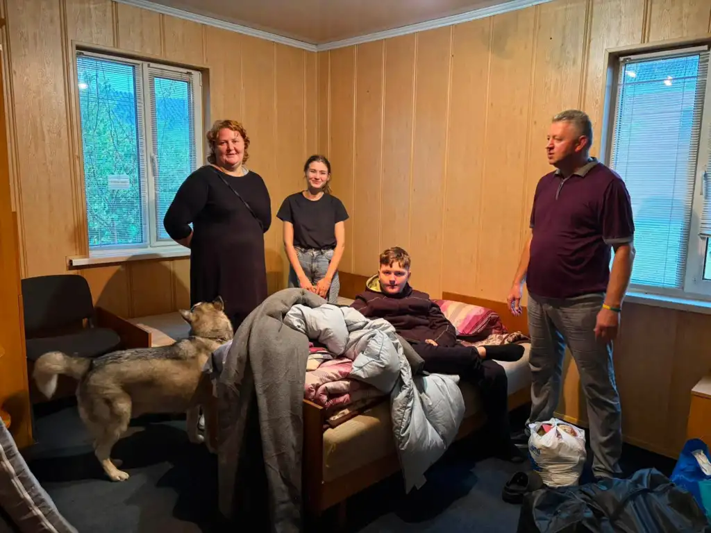 Чотири переселенці та великий собака в кімнаті з дерев’яними стінами в Рокитному